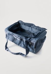 Μπλε μαλακή δερμάτινη τσάντα duffel με διπλές χειρολαβές και κεντρικό φερμουάρ ανοιχτό, που δείχνει άδειο εσωτερικό.