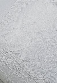 Tessuto in pizzo di colore grigio chiaro con motivi floreali, caratterizzato da una finitura liscia e dettagli delicati lungo i bordi.