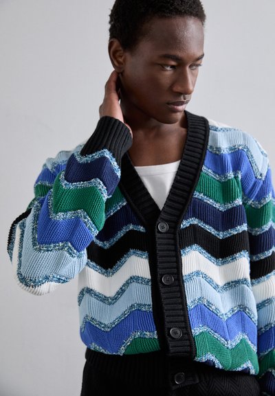 Colorful zigzag-patterned knit cardigan featuring a button-down front, ribbed black collar, and a mix of blue, green, and white hues.