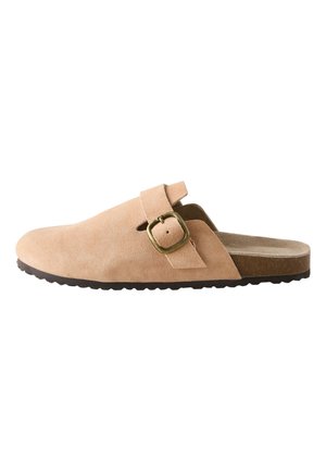 Sabot en daim beige avec bride à boucle réglable et semelle noire texturée.
