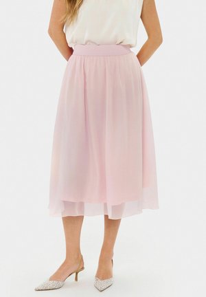 Gonna di chiffon rosa con cintura elastica, lunghezza al ginocchio, con un design a strati. Abbinata a décolleté a punta con accenti argentati.