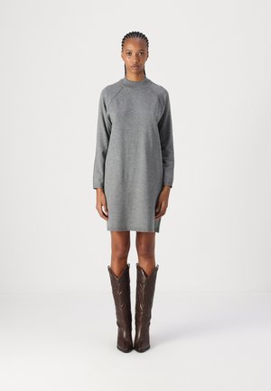 Gray, long-sleeve dress with a relaxed fit and round neckline, paired with knee-high brown cowboy boots featuring intricate patterns.