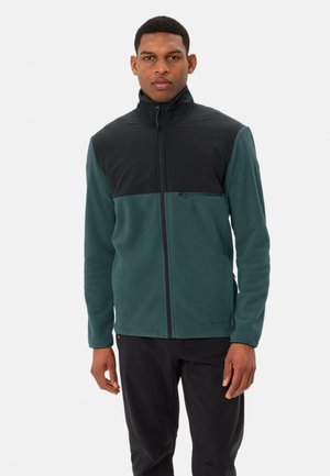 Fleece jack met een groene onderkant en een zwarte bovenkant, volle rits en een klein borstzakje. Glad van textuur met lange mouwen.