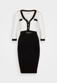 Svart och vit knälång klänning med V-ringning, trekvartsärmar och dekorativa knappar. Har ett bälte i midjan och kontrasterande detaljer.