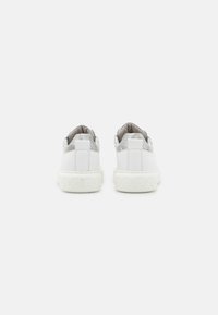 Sneakers bianche con un accento texturizzato argento sul tallone, forma arrotondata e suola in gomma caratterizzata da un motivo geometrico sul fondo.