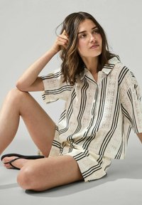 Set di camicia a maniche corte con colletto e pantaloni corti in crema con righe nere. Realizzato in tessuto leggero con un motivo testurizzato.