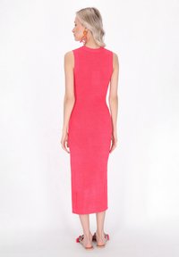 Abito fitted, senza maniche, di lunghezza intermedia in tessuto testurizzato di un vivace rosa. Presenta un collo alto e una silhouette elegante.