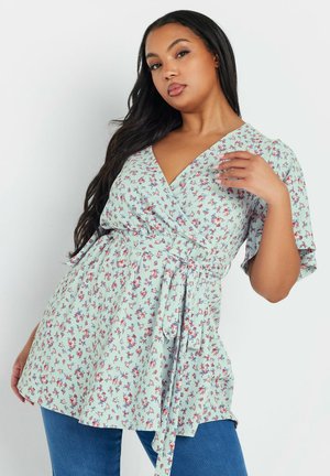 Floral wrap blouse in light blue with short sleeves, featuring a belt at the waist, small red and pink flower patterns, and a V-neckline.