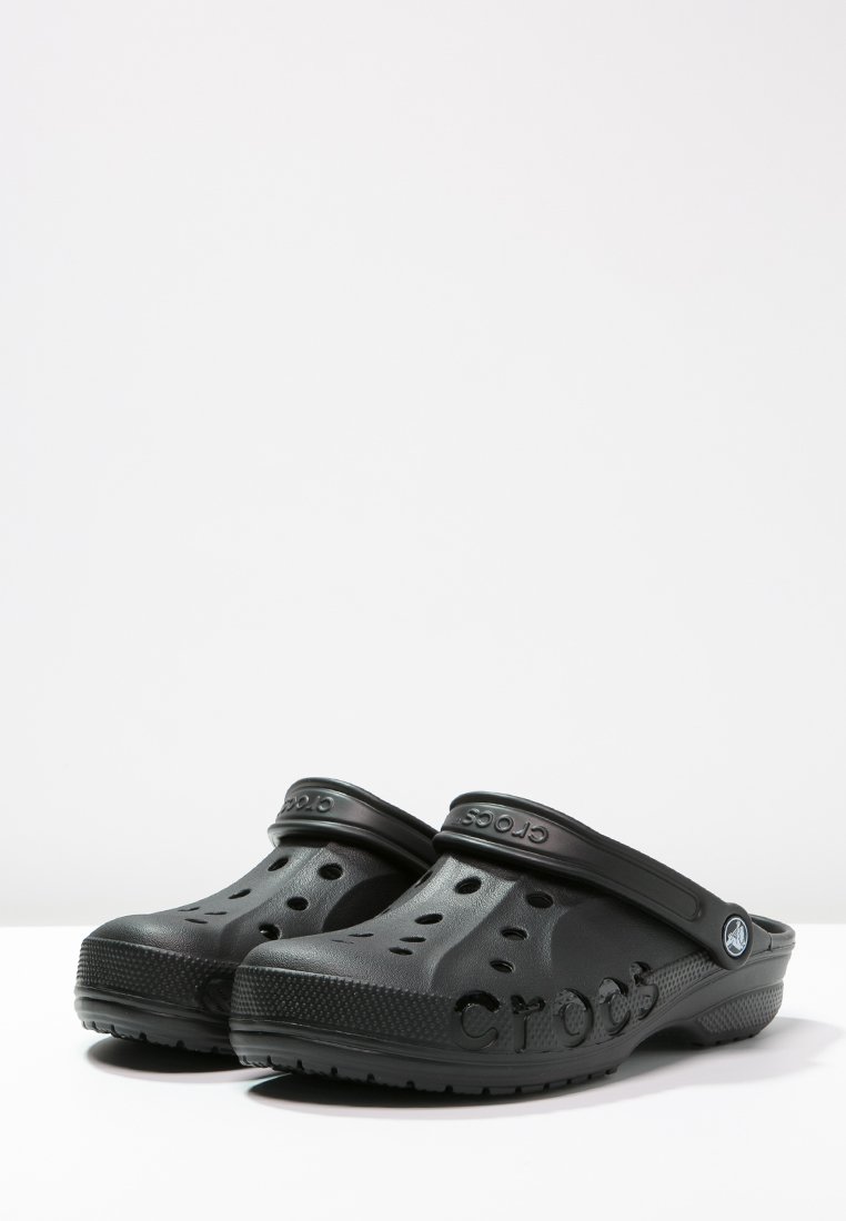 Zuecos negros de Crocs con agujeros de ventilación, correas ajustables en el talón y suelas texturizadas sobre un fondo blanco.