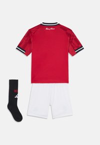 Maglia sportiva rossa con colletto a righe bianche e nere, abbinata a pantaloni corti bianchi e calze nere con testo e logo rossi.