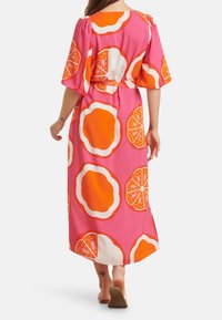 Maxikleid aus pinkem Stoff mit großen Orangenscheiben und weißen Akzenten. Puffärmel und ein gebundenes Taillenband vervollständigen das Design.