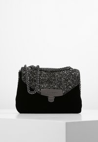 Borsa a mano in velluto nero con un flap superiore luccicante, hardware argento e una tracolla a catena, offrendo una forma rettangolare compatta.