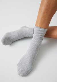 Graue Baumwollsocken mit ribbeltem Bündchen, die eine glatte Oberfläche und ein klassisches Knöchel-Design aufweisen.