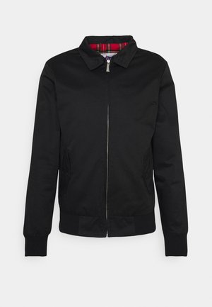Chaqueta bomber negra con cremallera frontal, puños y dobladillo acanalados. Presenta un forro de cuadros rojos y dos bolsillos laterales. Textura suave, diseño minimalista.