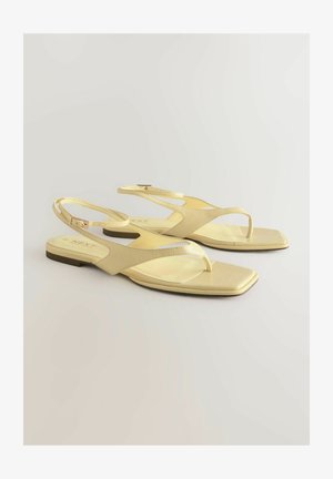 Sandales plates jaunes avec une tige en simili cuir texturé, design à lanière entre les orteils et une sangle de cheville avec une petite boucle. Forme de pied carrée, style minimaliste.