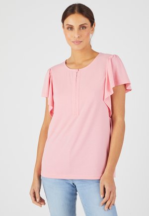 Roze top met korte mouwen, versierd met geplooide ruffle-details, ronde halslijn en een knoopje aan de voorkant. De stof lijkt zacht en glad.