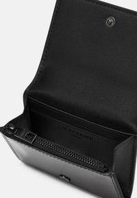 Portafoglio in pelle nera con una superficie liscia, scomparto con zip e chiusura a scatto in metallo. L'interno presenta il logo del brand impresso sulla fodera.