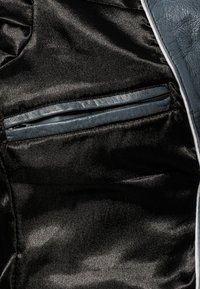 Schwarzer Satin-Stoff mit einer Reißverschlusstasche, verziert mit einem kontrastierenden blauen Kunstlederbesatz und glatter Textur.