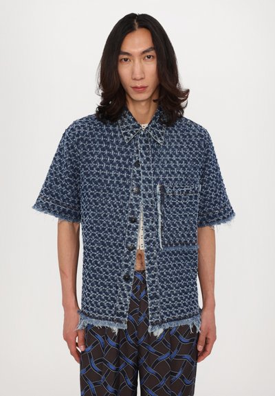Denim short-sleeve shirt with a textured pattern, frayed hem, blue hue, and a front pocket. Features a button-front closure and contrast stitching.