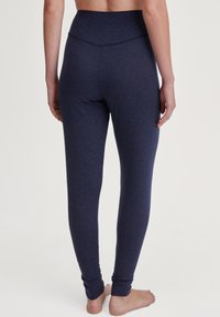 Marineblauwe legging van zacht, rekbaar materiaal met een hoge tailleband en een aansluitend ontwerp, dat smal toeloopt bij de enkels. Heeft een naadloze constructie.