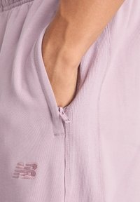 Hellviolette Jogging-Shorts mit seitlicher Reißverschlusstasche, weichem Stoff, gerippten Details und einem kleinen, bestickten Logo.