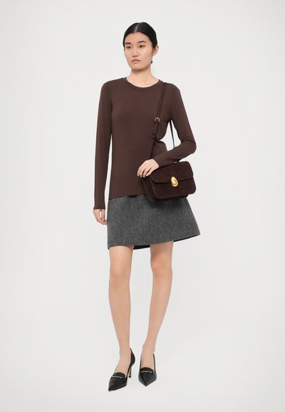 Bruine lange mouwen top, grijze rok en zwarte hoge hakken. Een donker tas met een gouden hardwareaccent maakt de outfit compleet. Eenvoudig, aansluitend ontwerp.