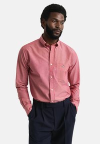 Rode chambray overhem met knopen en een zak, met een klassieke kraag en lange mouwen, gecombineerd met donkerblauwe broek.