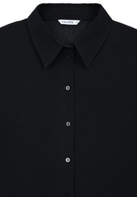 Chemise noire à boutons en tissu texturé. Présente un col classique, six boutons et une étiquette portant l'inscription « CALLIOPE » dans le col.