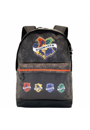 Mochila negra con un gran logo de Hogwarts, un acento en el cremallera naranja y los logos de las casas (Gryffindor, Hufflepuff, Ravenclaw, Slytherin) en la parte frontal.