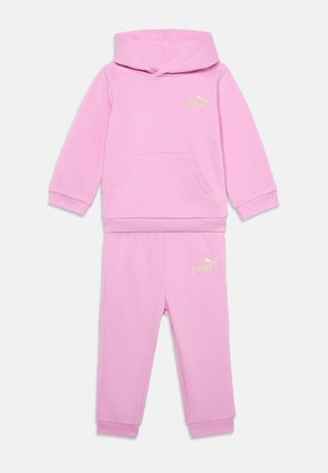 Różowa bluza z kapturem i długim rękawem oraz pasujące spodnie z białym logo Puma na piersi i lewym udzie, pokazane na płasko na białym tle.