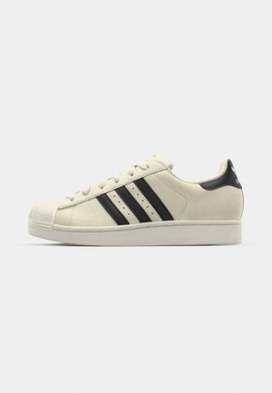 Hvite lær sneakers med svarte striper, rund tå, gummisåle, teksturert overdel og lissystem. Har logo på hælen.