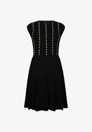 Crna pletena haljina s tijelom krojenim uz tijelo i suknjom u zvonastom kroju, s okomitim redovima ukrasnih krljušti na prednjem dijelu.