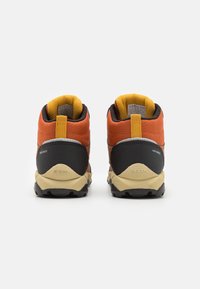 Scarpe da hiking arancioni e nere con colletto imbottito, tessuto testurizzato, dettagli gialli e suola in gomma beige, viste da dietro.