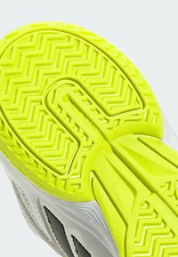 Suola di scarpa in gomma di un vivace giallo con un motivo a zigzag per la trazione; presenta una parte superiore liscia e bianca con accenti neri; progettata per una buona presa.
