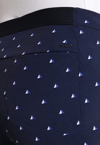 Marina shorts med ett geometriskt triangelmönster i blått och vitt. Har en svart midja och RLX-logotyper på bakfickan.