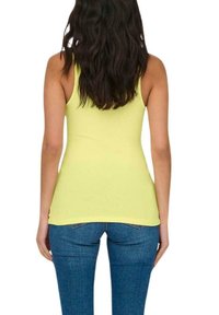 Top de tirantes amarillo acanalado con un diseño ajustado, combinado con jeans azules. La parte superior tiene un escote redondeado y es sin mangas.