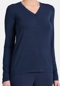 Maglietta a maniche lunghe blu navy con scollatura a V, dotata di una patta con quattro bottoni neri e una texture liscia e morbida.