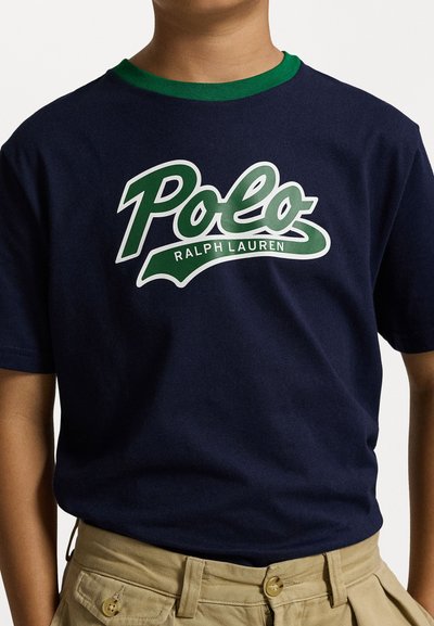 Mornarsko modra bombažna majica s zelenim rebrastim ovratnikom, ki ima velik bel in zelen "Polo Ralph Lauren" logotip čez prsa.