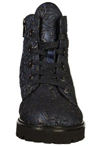 Mustat nilkkurit, joissa on teksturoitu, kohokuvioitu pinta, nauhanyöritettävä muotoilu ja kiinteä musta kumipohja. Pintakäsittelyllä on metallinhohtoa.