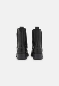 Svarta läderankelstövlar med elastiska sidopaneler, rundade tår och dragflikar. Robust gummisula och slät yta.