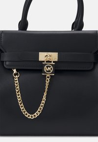 Borsa a tracolla in pelle nera con un design strutturato, caratterizzata da un accento con lucchetto dorato e dettagli in catena, texture liscia e manici superiori.