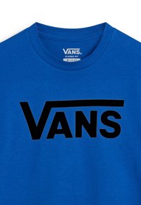 Sininen puuvillapaita, jossa on silmiinpistävä musta "VANS" -logo rinnan kohdalla, klassisella pyöreällä kaula-aukolla ja lyhyillä hihoilla.