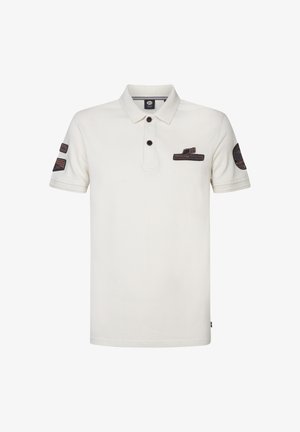 Polo de culoare crem, cu guler și trei butoane. Două petice pe umăr cu accente închise și detalii de text sunt vizibile.