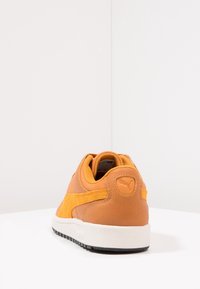 Baskets en cuir marron avec des accents en daim jaune. Présentent une semelle en caoutchouc blanc et un contre-fort texturé, affichant une forme arrondie.