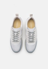 Lichtgrijze sportschoenen met een glad, synthetisch bovenwerk, contrasterende blauwe accenten, ronde neus en platte veters. Gevoerde zolen zichtbaar aan de binnenkant.