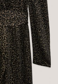 Robe noire en tissu texturé avec des motifs circulaires dorés, une ceinture à la taille et des manches longues. Drapé élégant avec une silhouette classique.