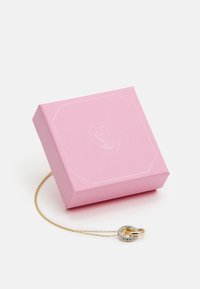 Roze sieradendoos met een gestructureerd oppervlak, bevat een gouden en zilveren ketting met een ronde hanger en sprankelende accenten.