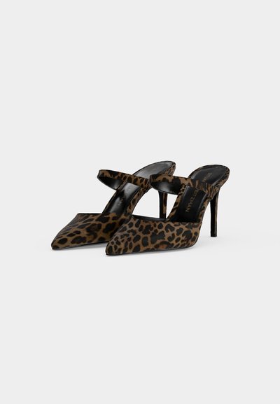 Paire de chaussures mules à talons hauts avec motif léopard et une seule bride sur le dessus sur fond blanc.
