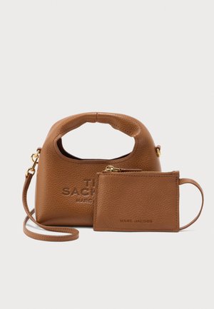 Hnědá kožená kabelka s kulatým držadlem, zdobená reliéfním logem. Součástí je sladěná pouzdro na karty se zipovým uzávěrem.