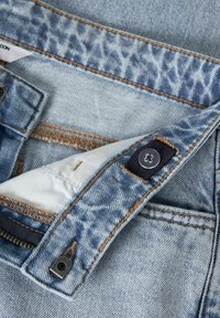 Cintura de jeans de mezclilla azul claro con detalle de estampado de leopardo, cierre de botón, cremallera visible y acentos de costura.